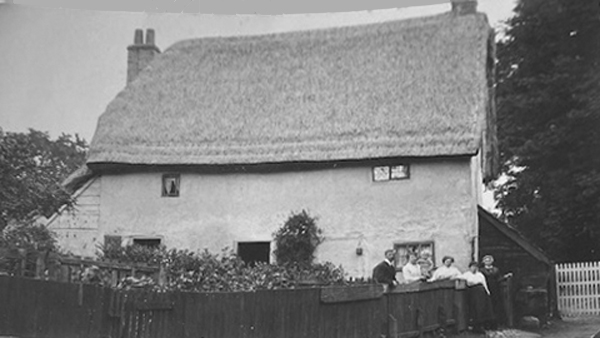 Thatched cottage with people standing in front